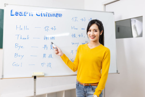 asian female teacher teach chinese language for foreign online through webcam in classroom